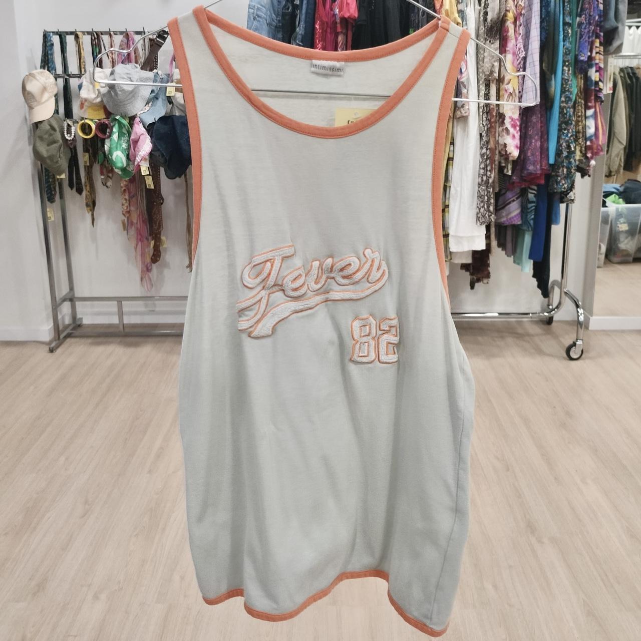 Vintage sleeveless tank top with orange trim and 'Fever 82' embroidery, thrift store setting