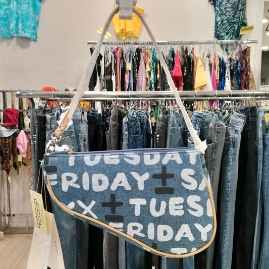 Blue denim bag with text hanging in a clothing store