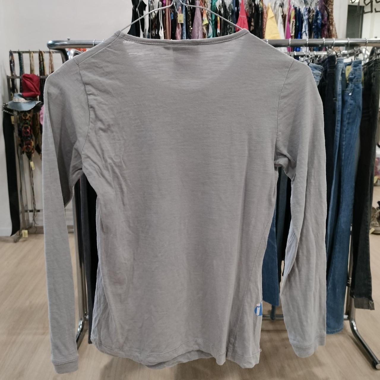 Grey long sleeve shirt on hanger in second hand fashion store
