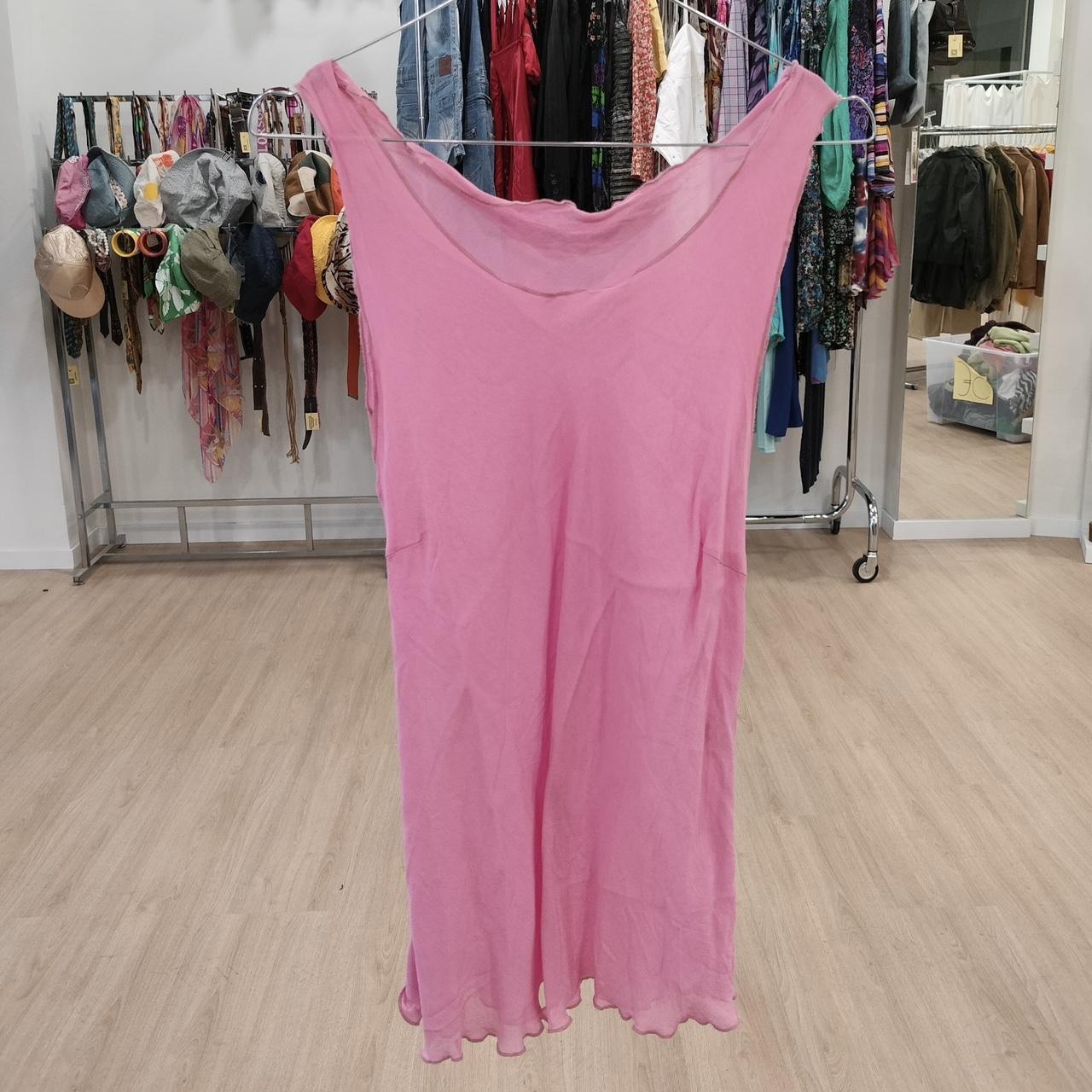 Bright pink sleeveless dress on hanger in second hand clothing store
