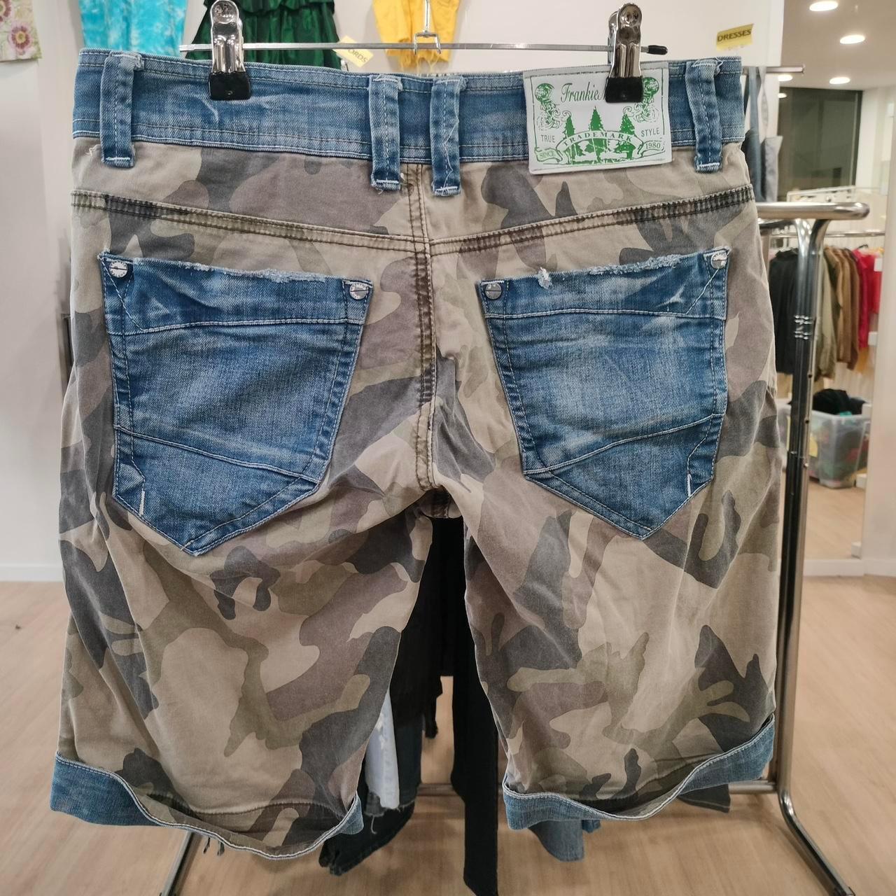 Camouflage shorts with blue denim back pockets displayed in a clothing store