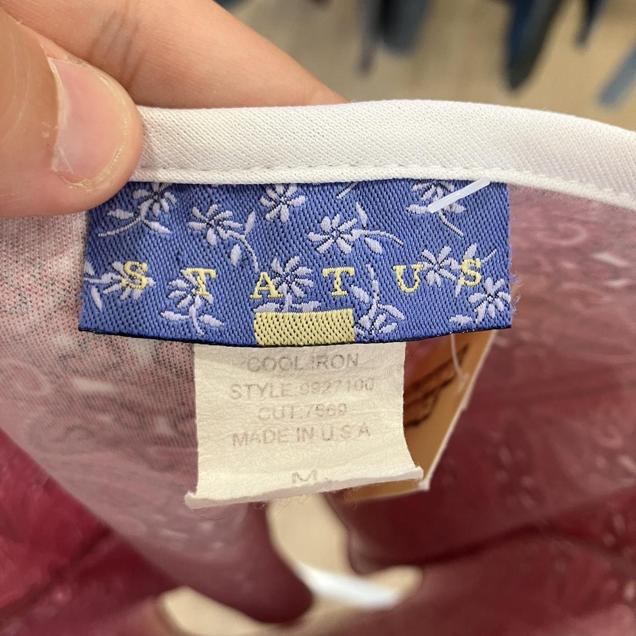 Close-up of a label with 'STATUS' branding on a garment