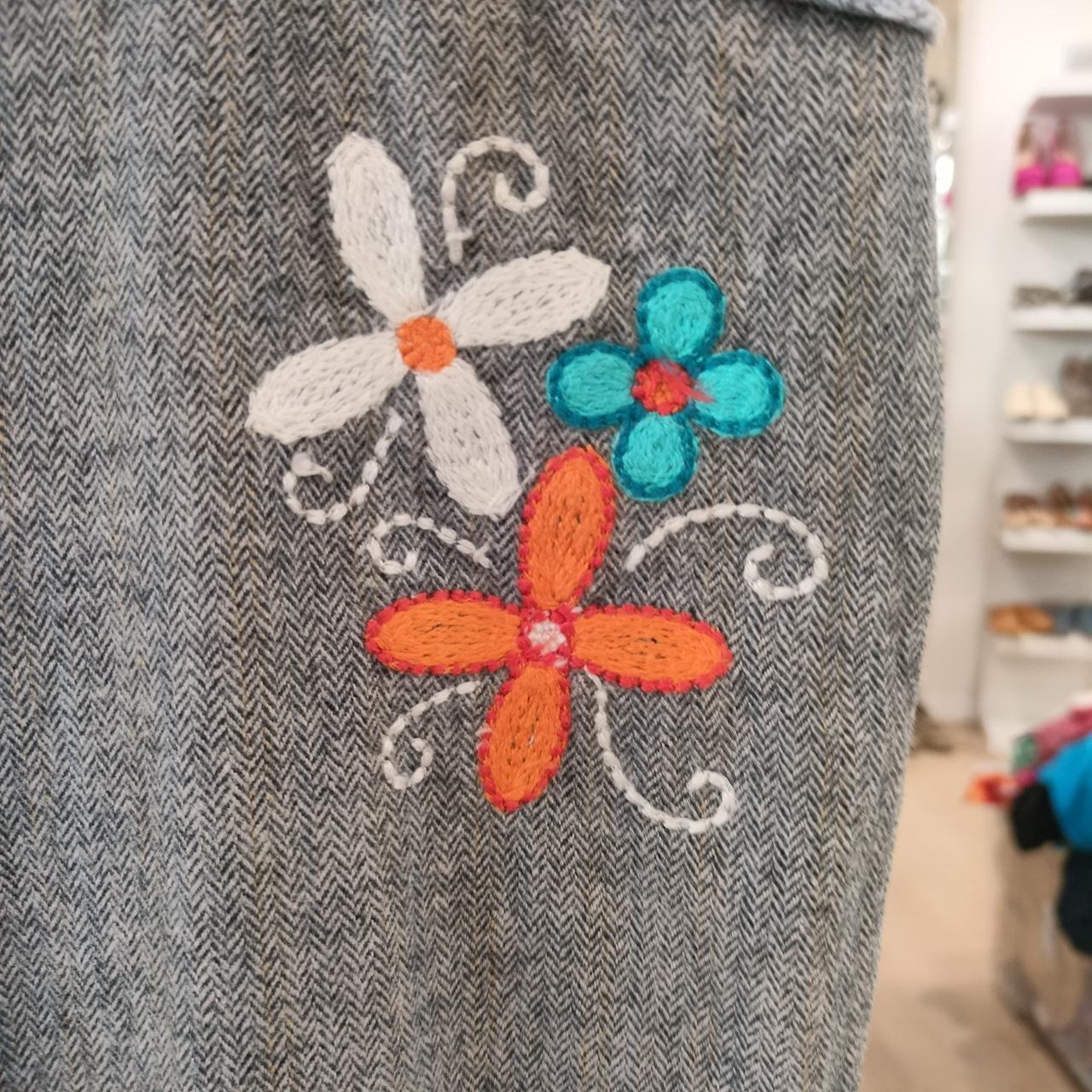 Gray textured fabric with embroidered flowers in orange, blue, and white