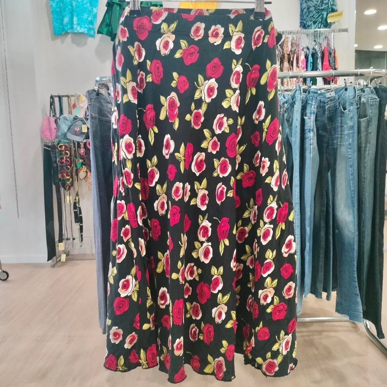 Black floral maxi skirt with red and white rose print on hanger in second hand shop