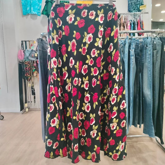 Black floral maxi skirt with red and white rose print on hanger in second hand shop