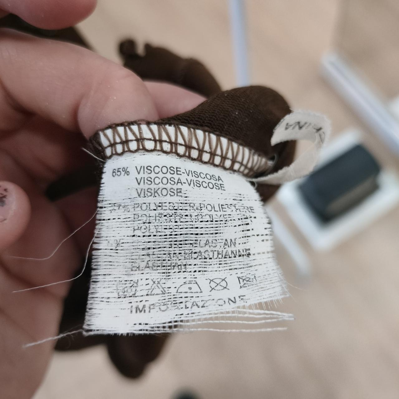 Close-up of a brown garment care label showing fabric composition with viscose blend