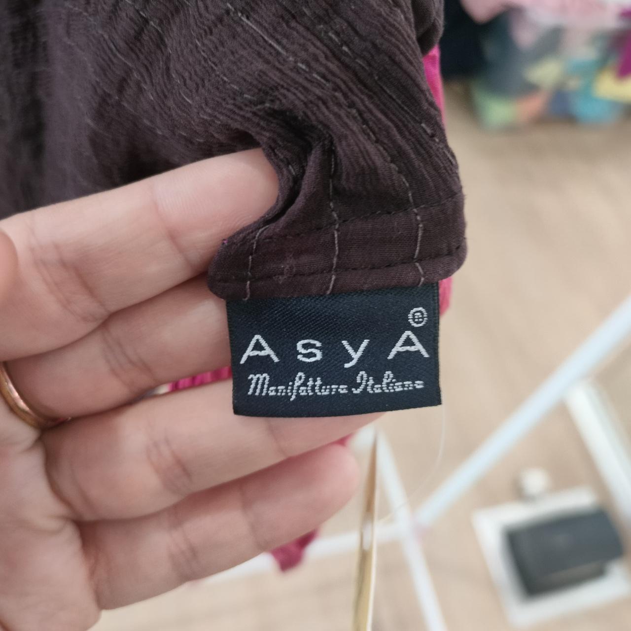 Hand holding a brown garment showing AsyA Manifatture Italiane clothing label