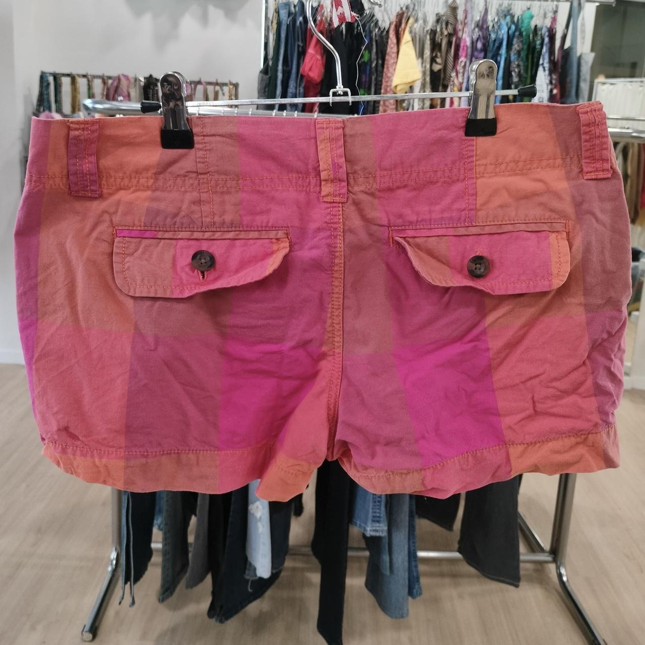 Pink shorts on a rack with other clothing in the background