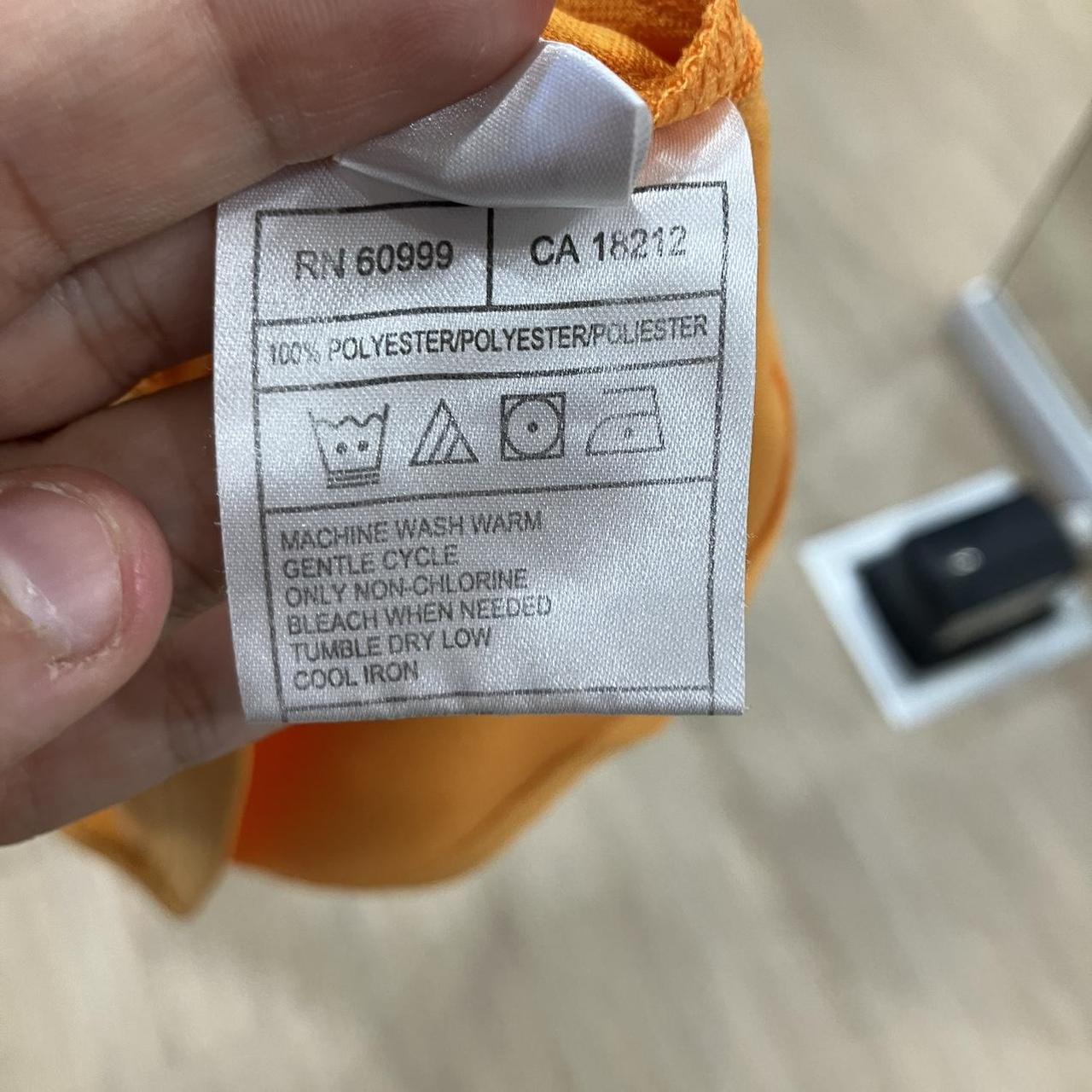 Clothing label with care instructions held by a hand against a blurred background