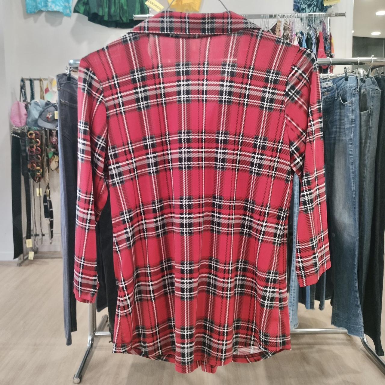 Red plaid long-sleeve shirt on hanger in second hand fashion store