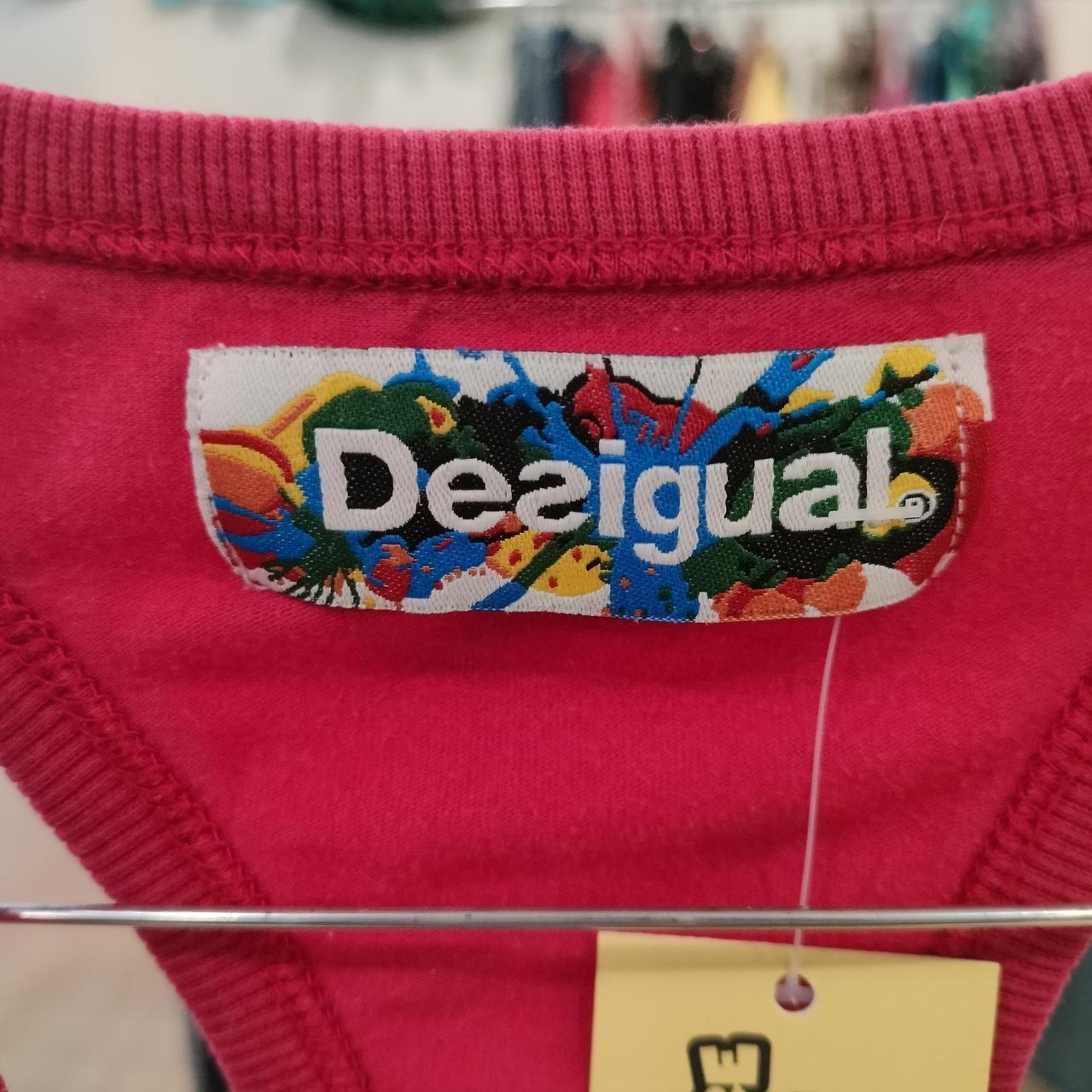 Close-up of a Desigual label on a red garment with a blurred background