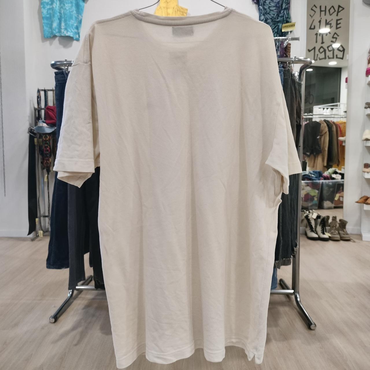 Beige long-sleeve shirt on a hanger in a store setting