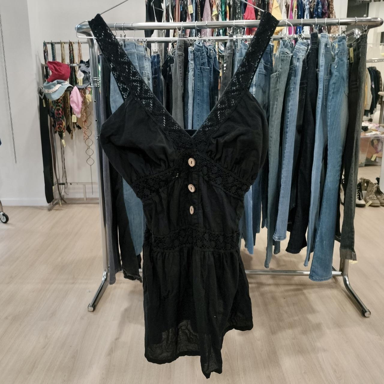 Black sleeveless dress with lace straps and button front, displayed in secondhand clothing store