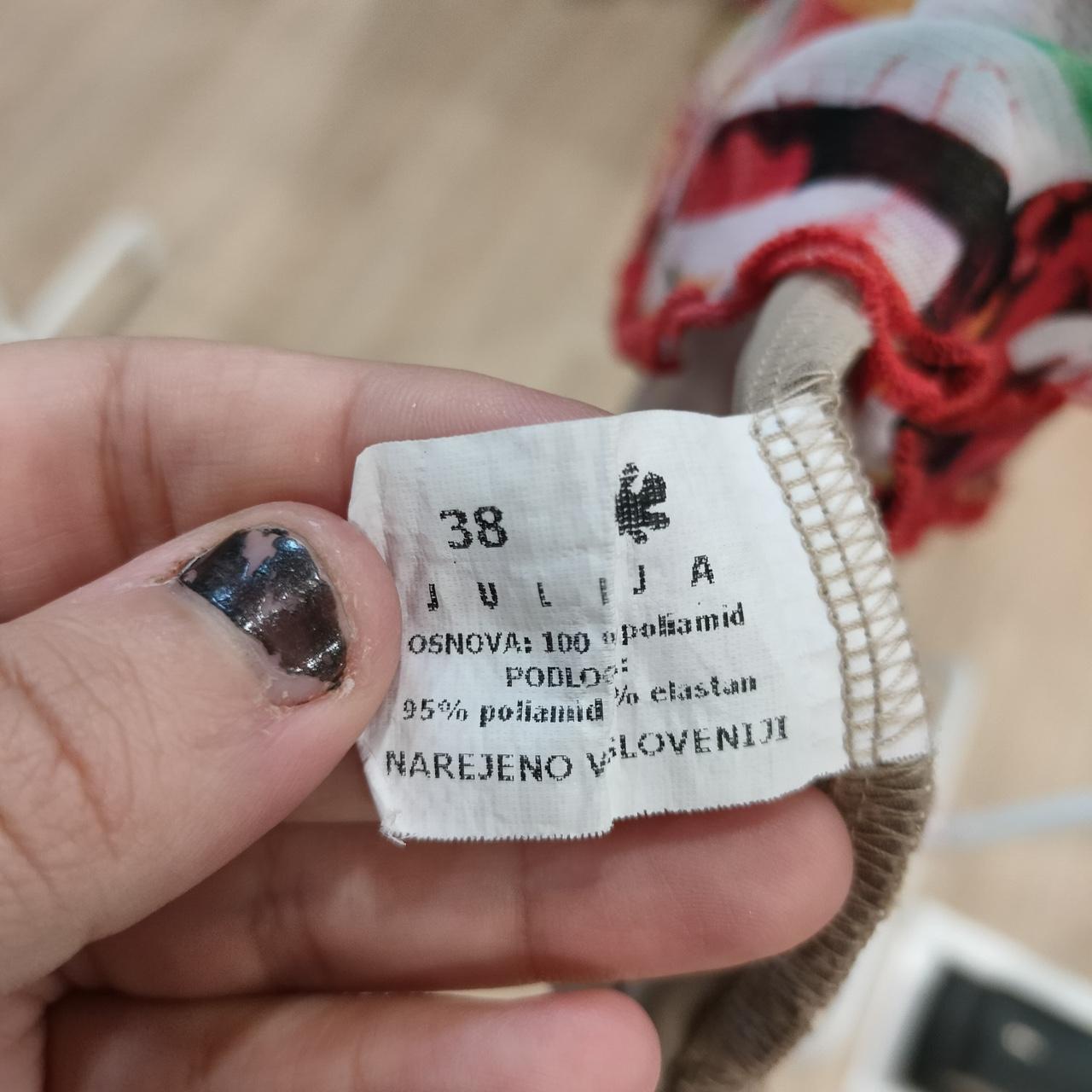 Closeup of clothing label with size 38, material details, and colorful fabric trim
