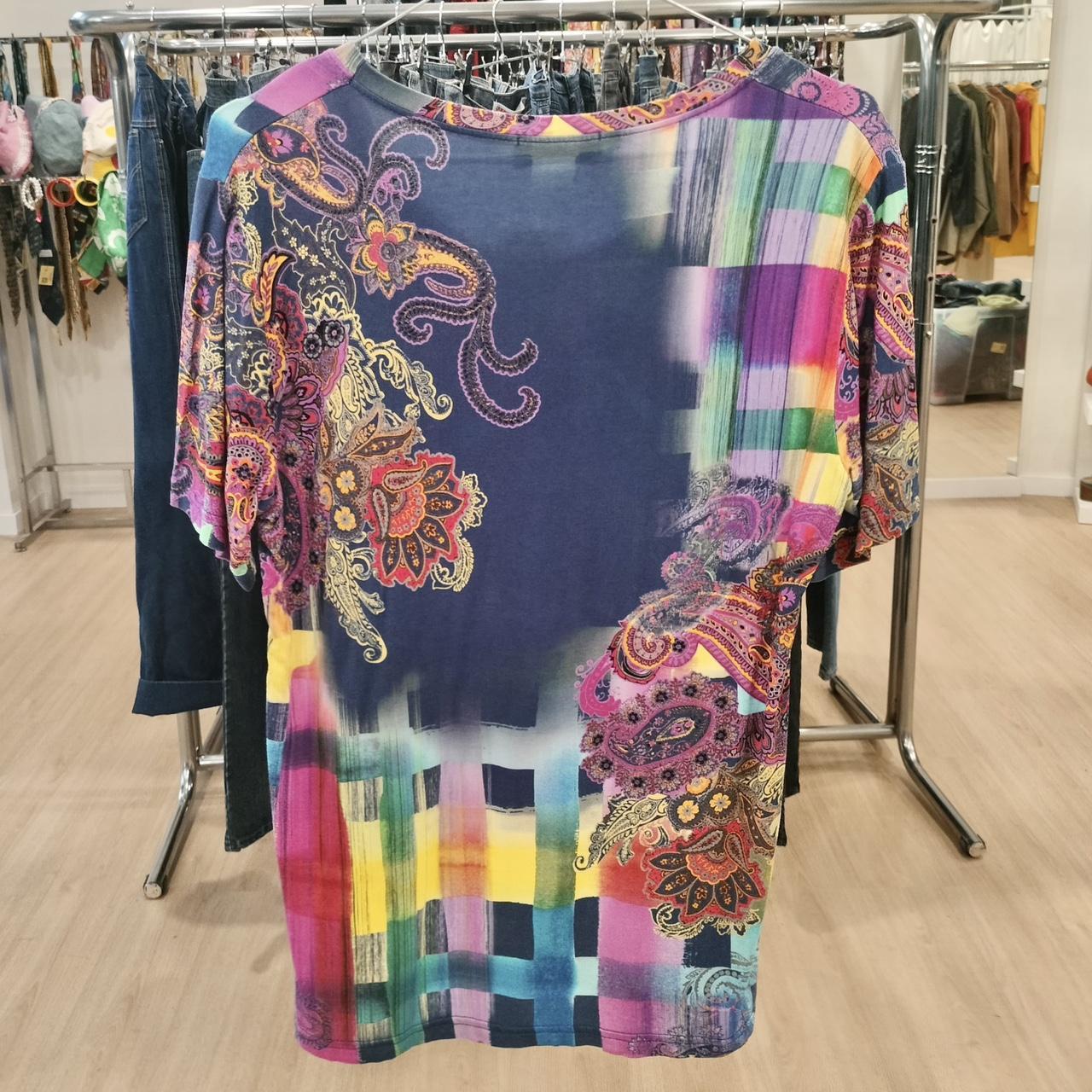 Colorful paisley and checkered print short sleeve shirt hanging in a second hand fashion store
