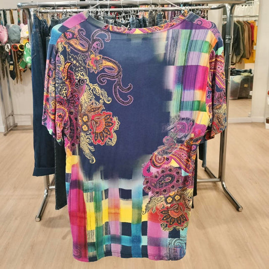 Colorful paisley and checkered print short sleeve shirt hanging in a second hand fashion store