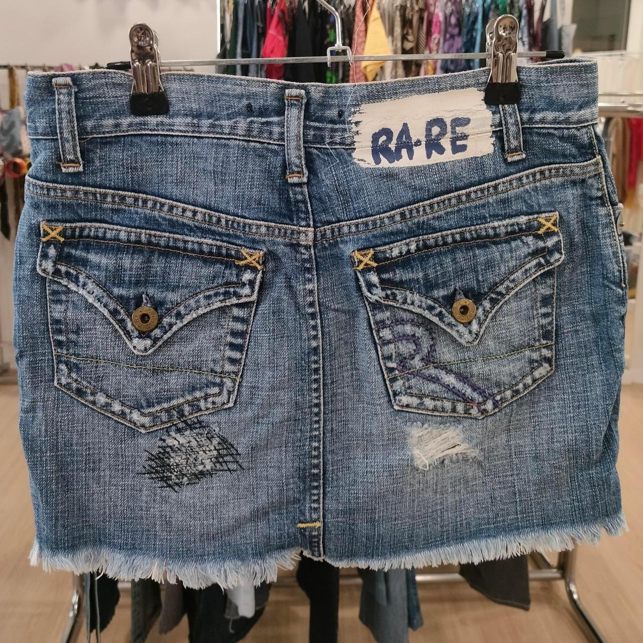 Distressed denim mini skirt with patchwork and frayed hem, labeled RARE on back waistband.