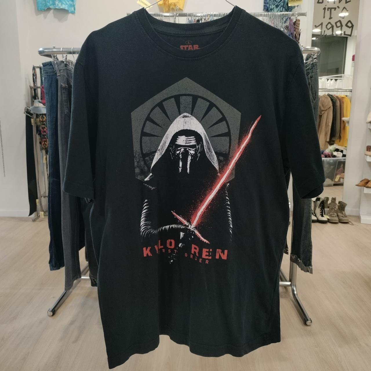 Black t-shirt with a graphic design of a character holding a lightsaber in a store setting