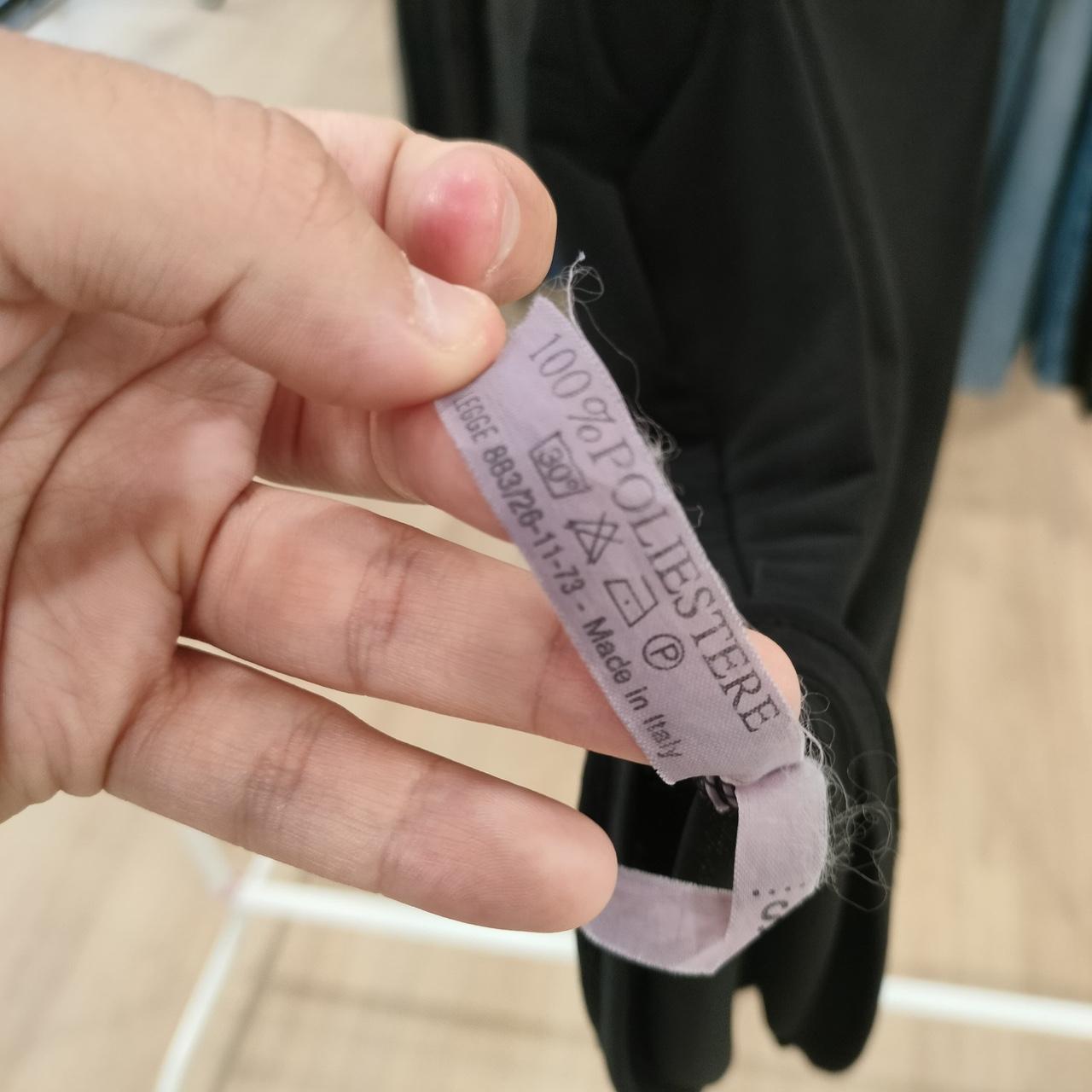 Hand holding a clothing label with text on a blurred background