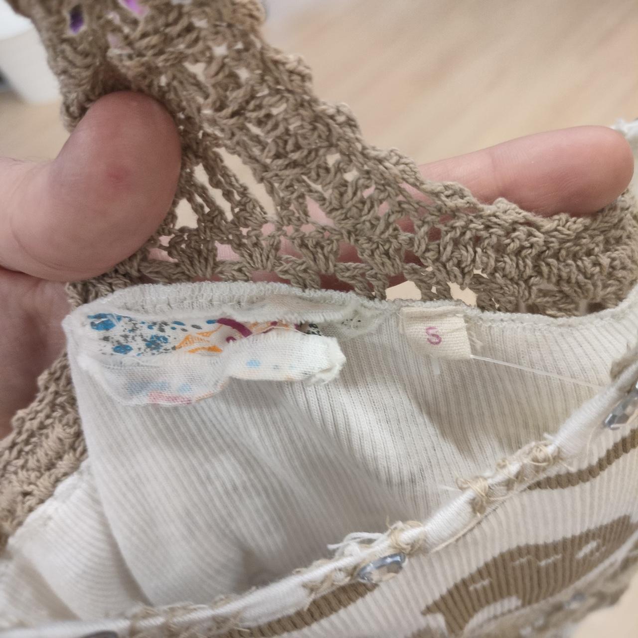 Hand holding crochet top with beige knit detail and visible size S label