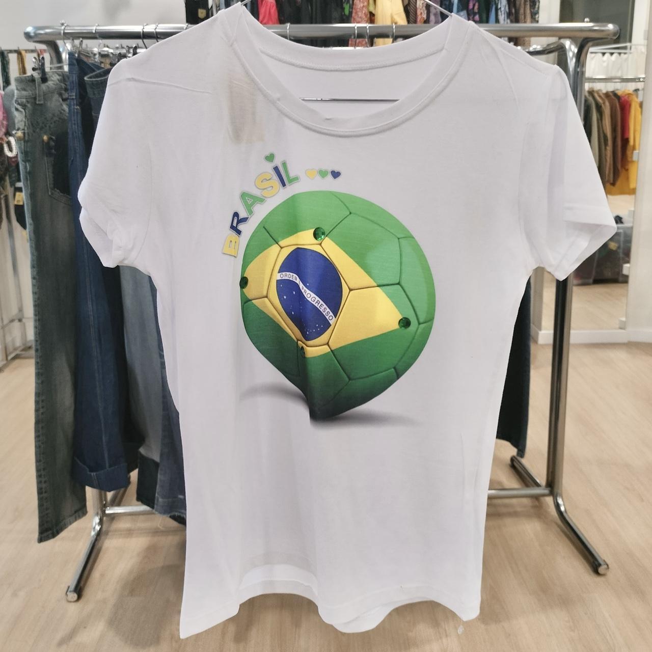White t-shirt with Brasil soccer ball graphic and colored hearts, displayed in a clothing store