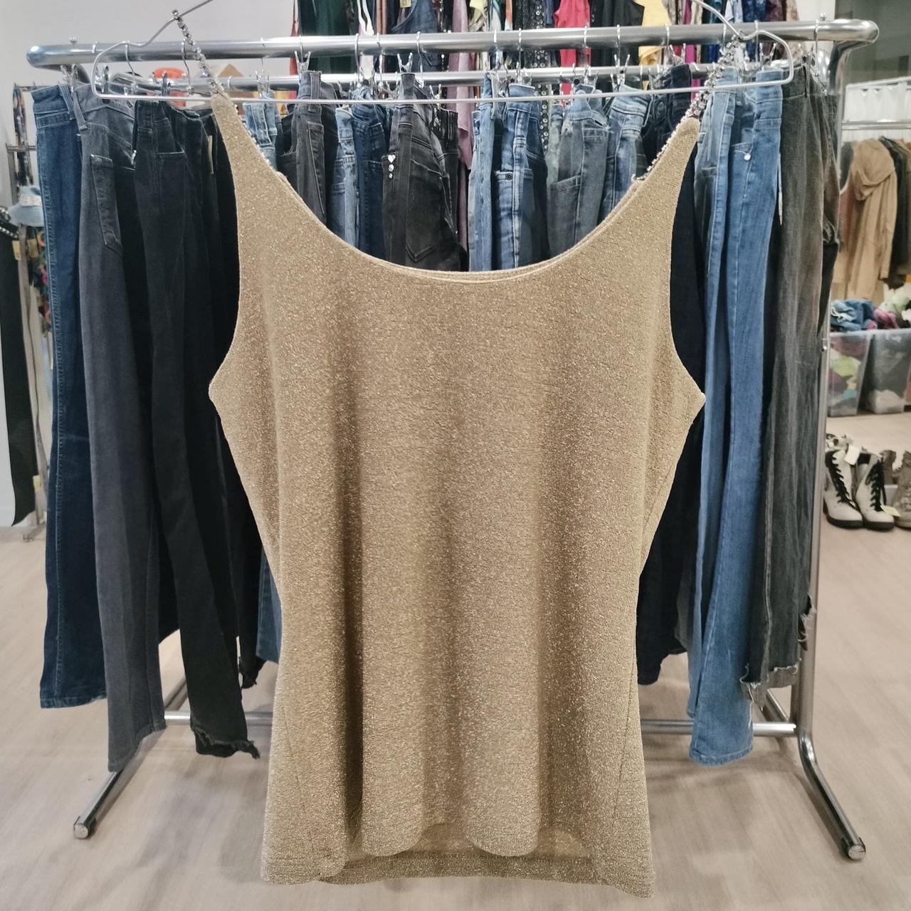 Beige tank top hanging on a rack with jeans in a store setting