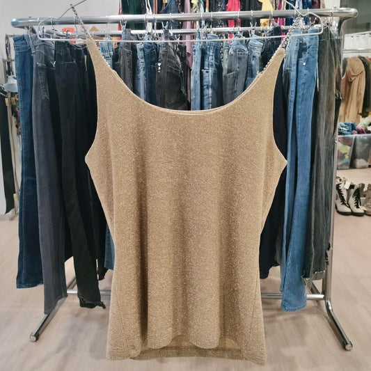 Beige tank top hanging on a rack with jeans in a store setting