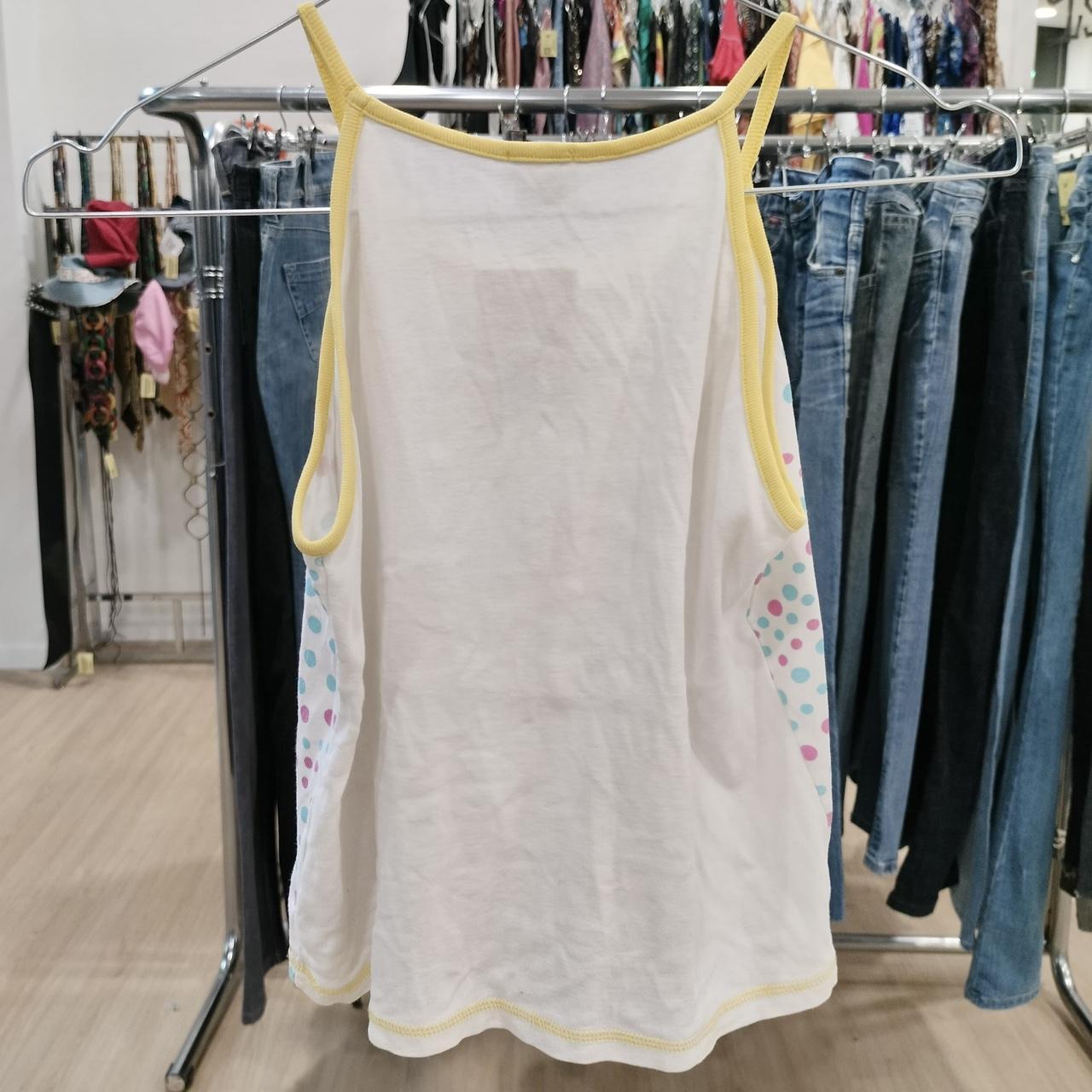 White sleeveless top with yellow straps and polka dot sides displayed in a clothing store
