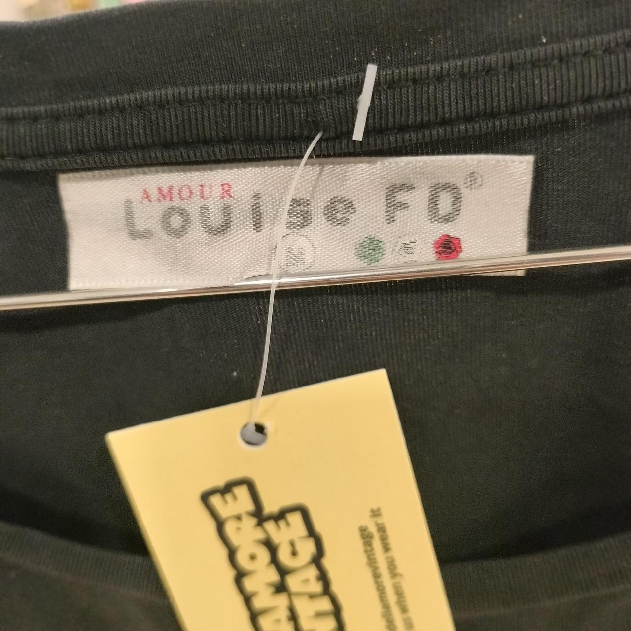 Close-up of a label on a black garment with 'Louise FD' branding