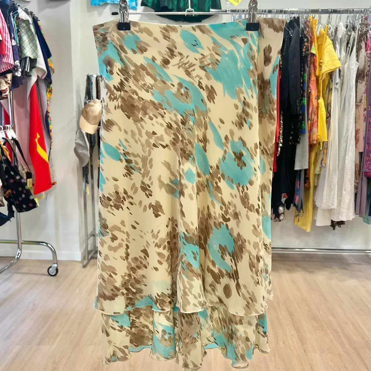 Beige midi skirt with blue and brown abstract print, layered hem, displayed in second hand fashion store