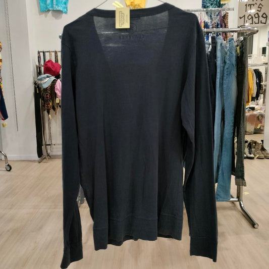 Black long-sleeve top hanging on a rack in a store setting