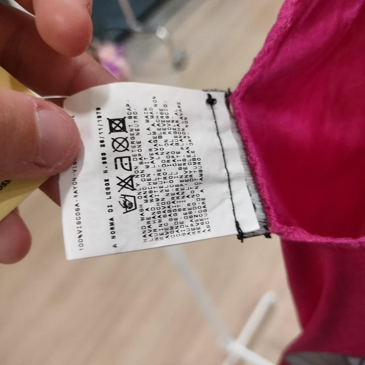 Close-up of a clothing label on a pink garment with a blurred background