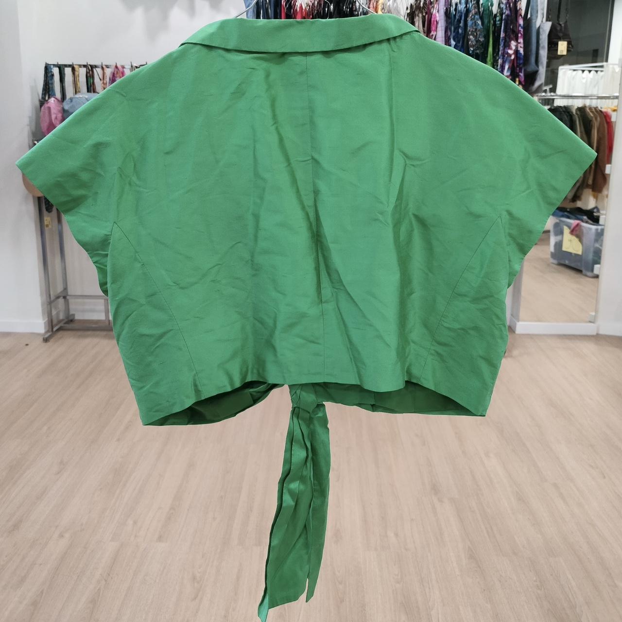 Green cape with a tie at the back on a wooden floor