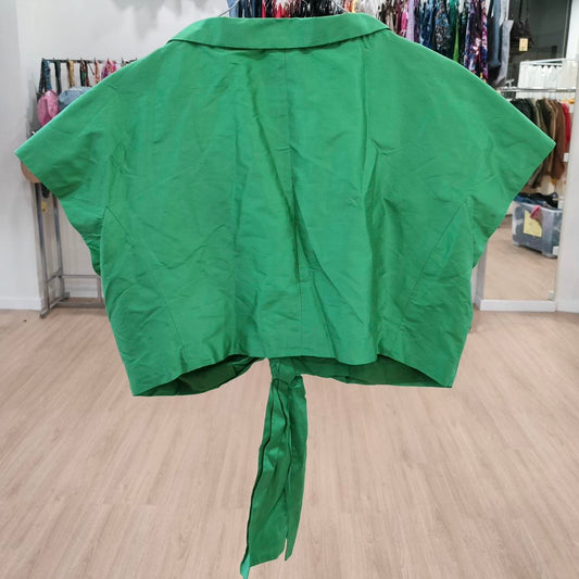 Green cape with a tie at the back on a wooden floor