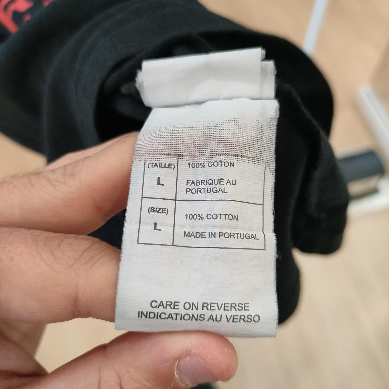 Clothing label held by a hand with text on it