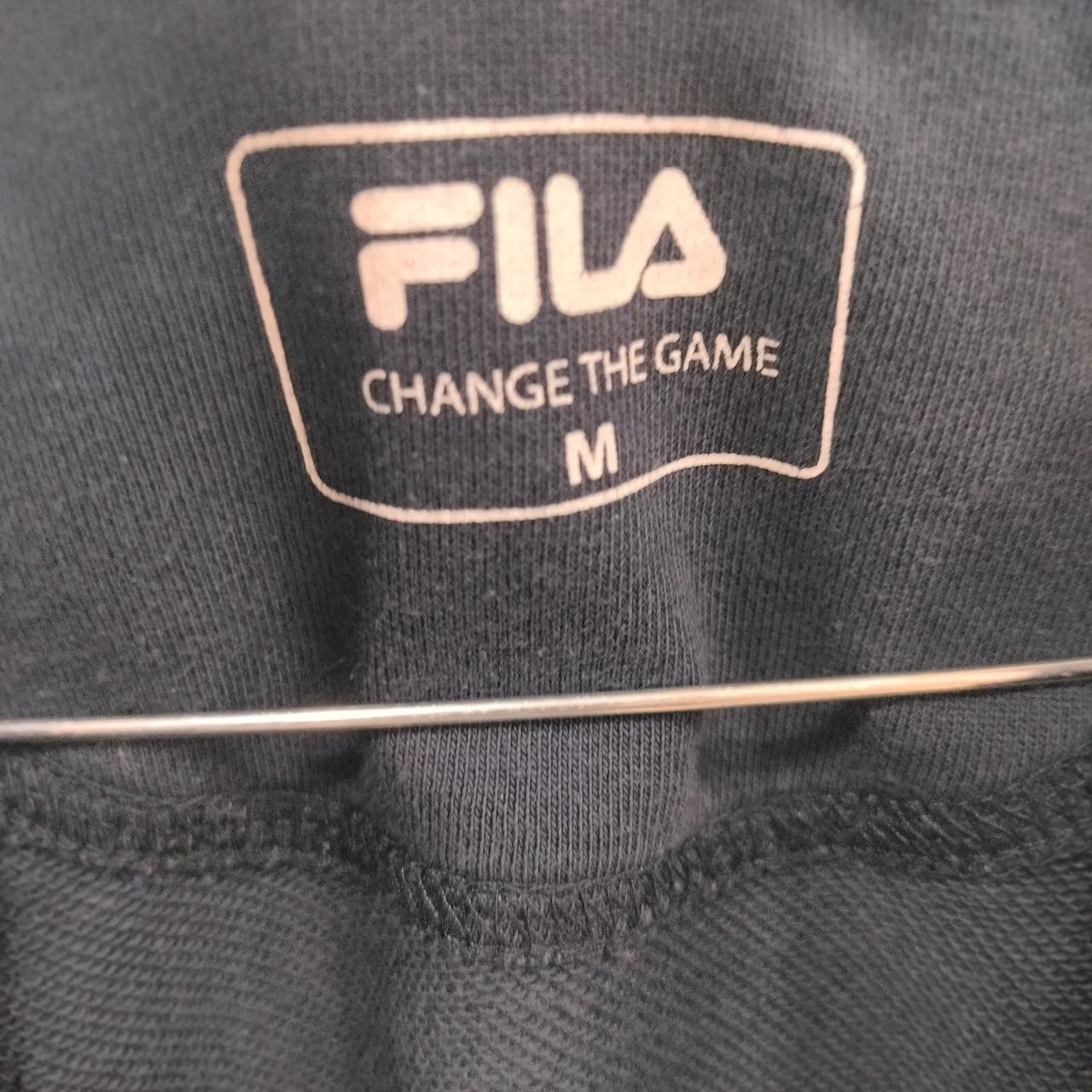 FILA logo on a dark fabric background with 'CHANGE THE GAME' text