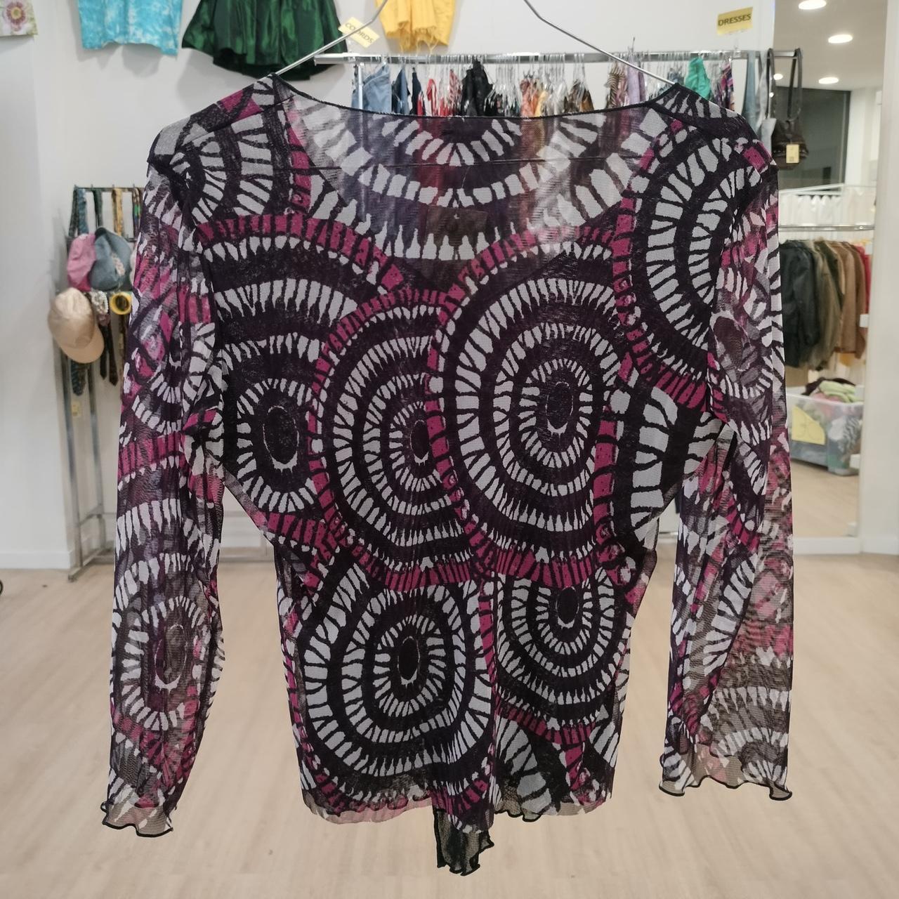 Sheer long sleeve top with bold circular black and magenta pattern, displayed in boutique