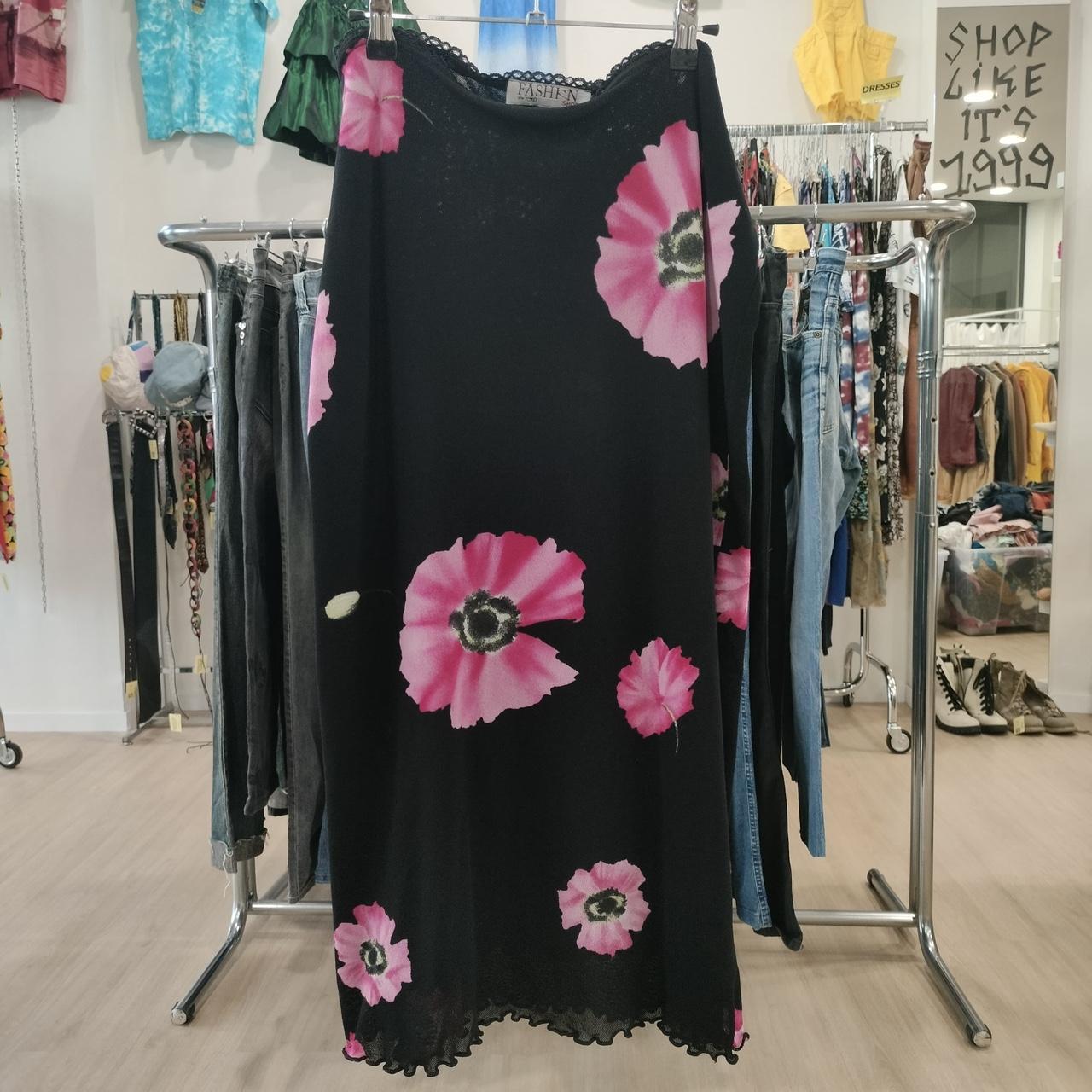 Black dress with pink floral patterns on a clothing rack in a store