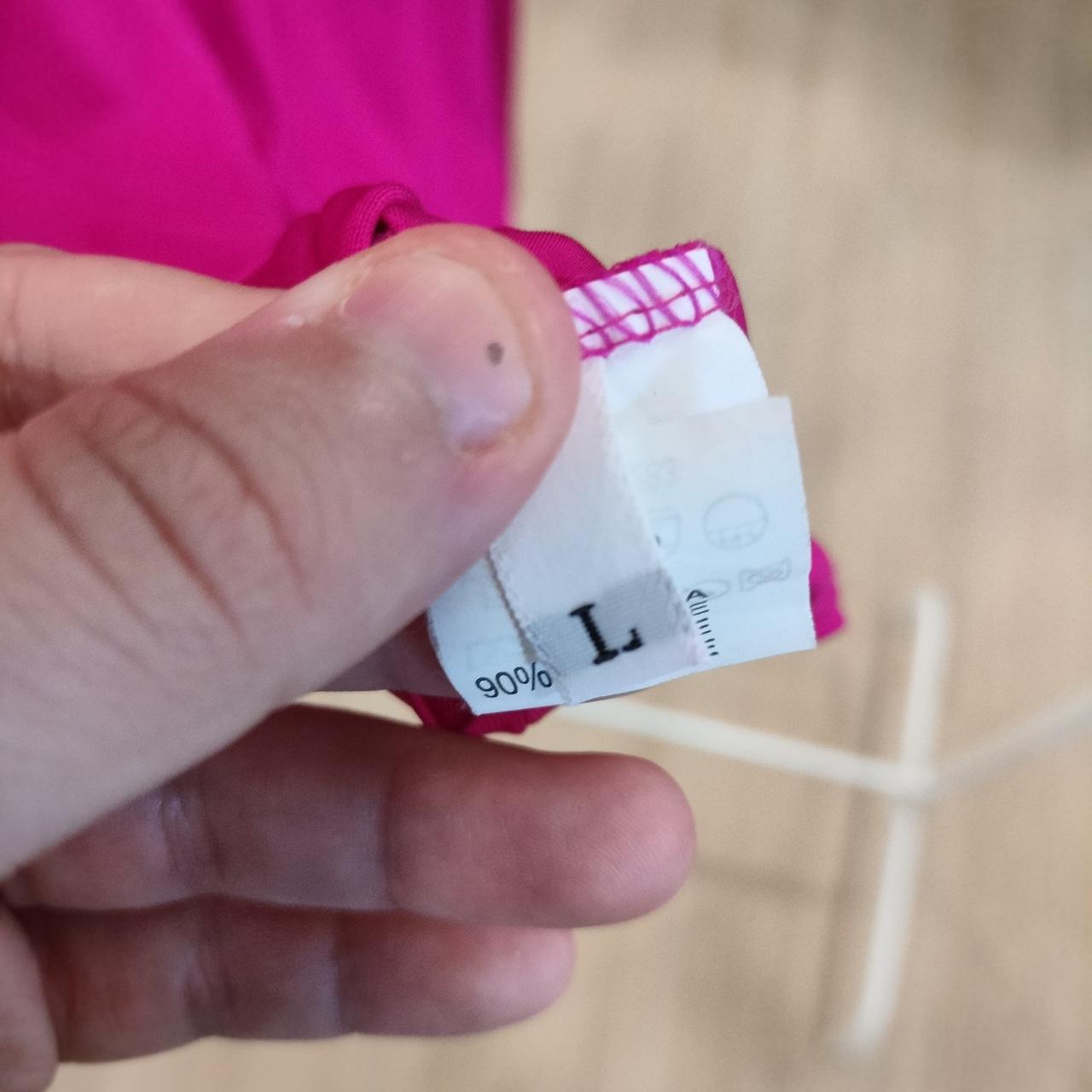 Close-up of a hand holding a clothing tag with brand name on a blurred background