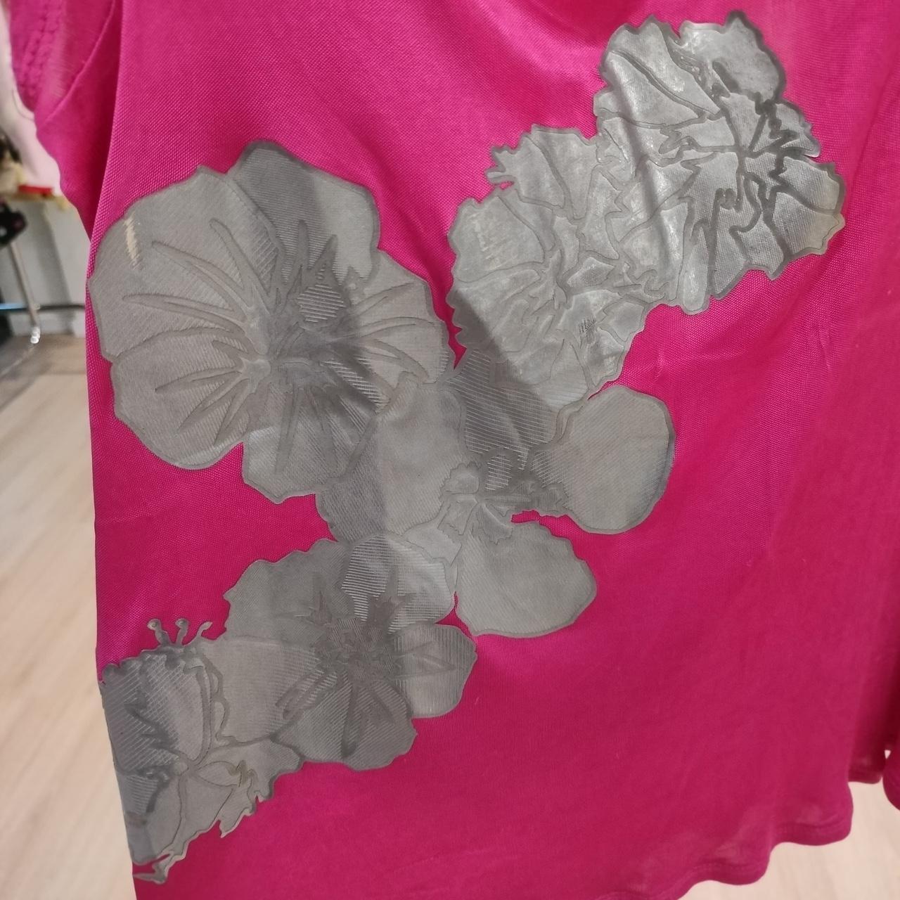 Pink fabric with gray floral patterns on a wooden floor background