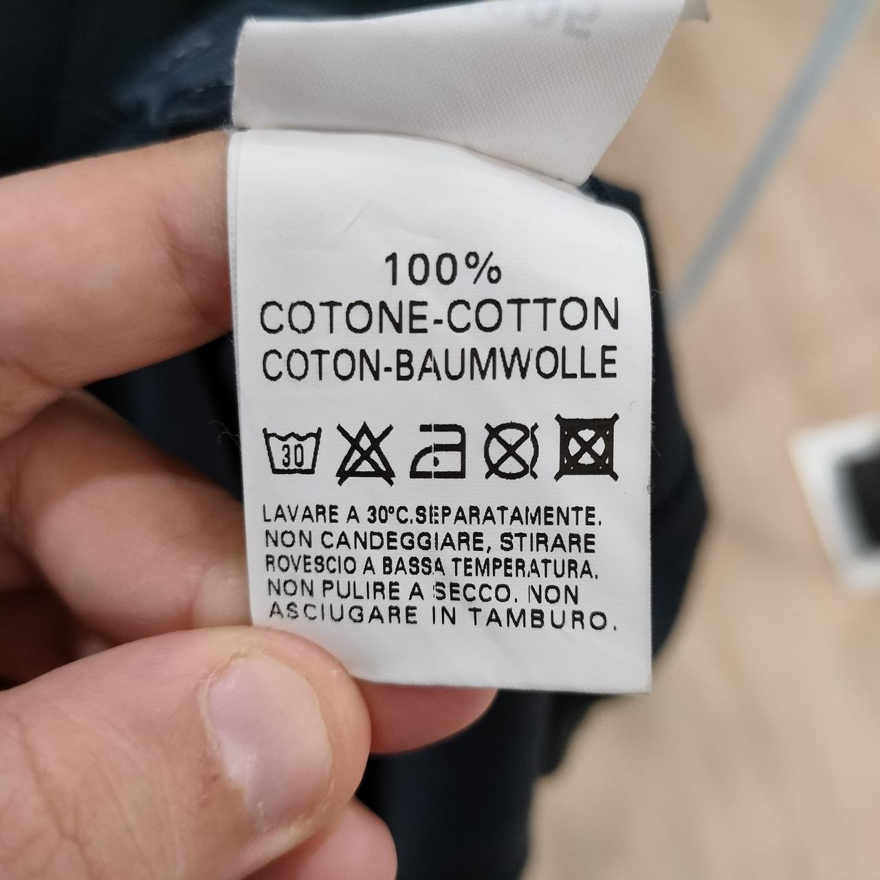 Clothing label with text and symbols held by a hand