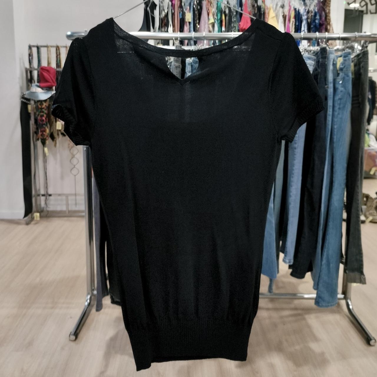Black t-shirt on a hanger with a clothing rack in the background