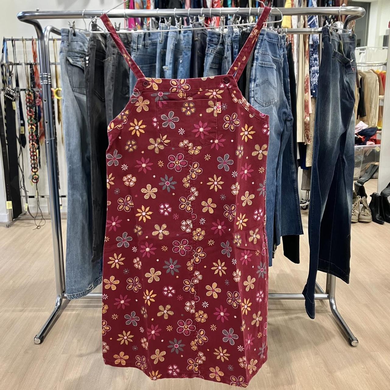Red floral print sleeveless dress on hanger in a second hand clothing store