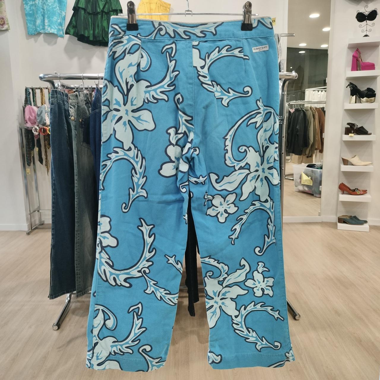 Blue pants with white floral patterns hanging on a rack in a store