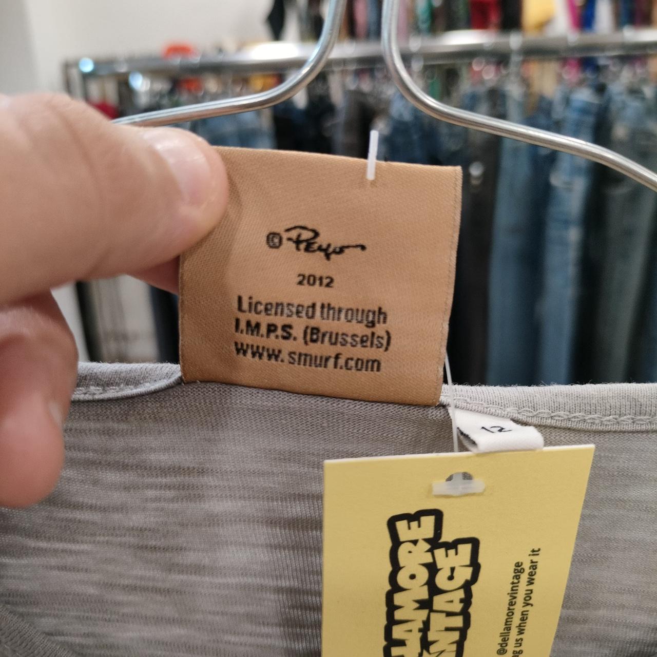 Close-up of a clothing label on a gray garment, showing licensing text and vintage tag