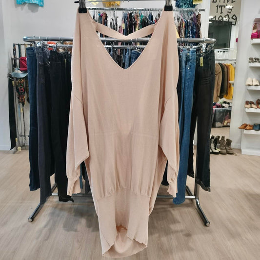 Beige dress hanging on a rack in a store with jeans and other clothing in the background
