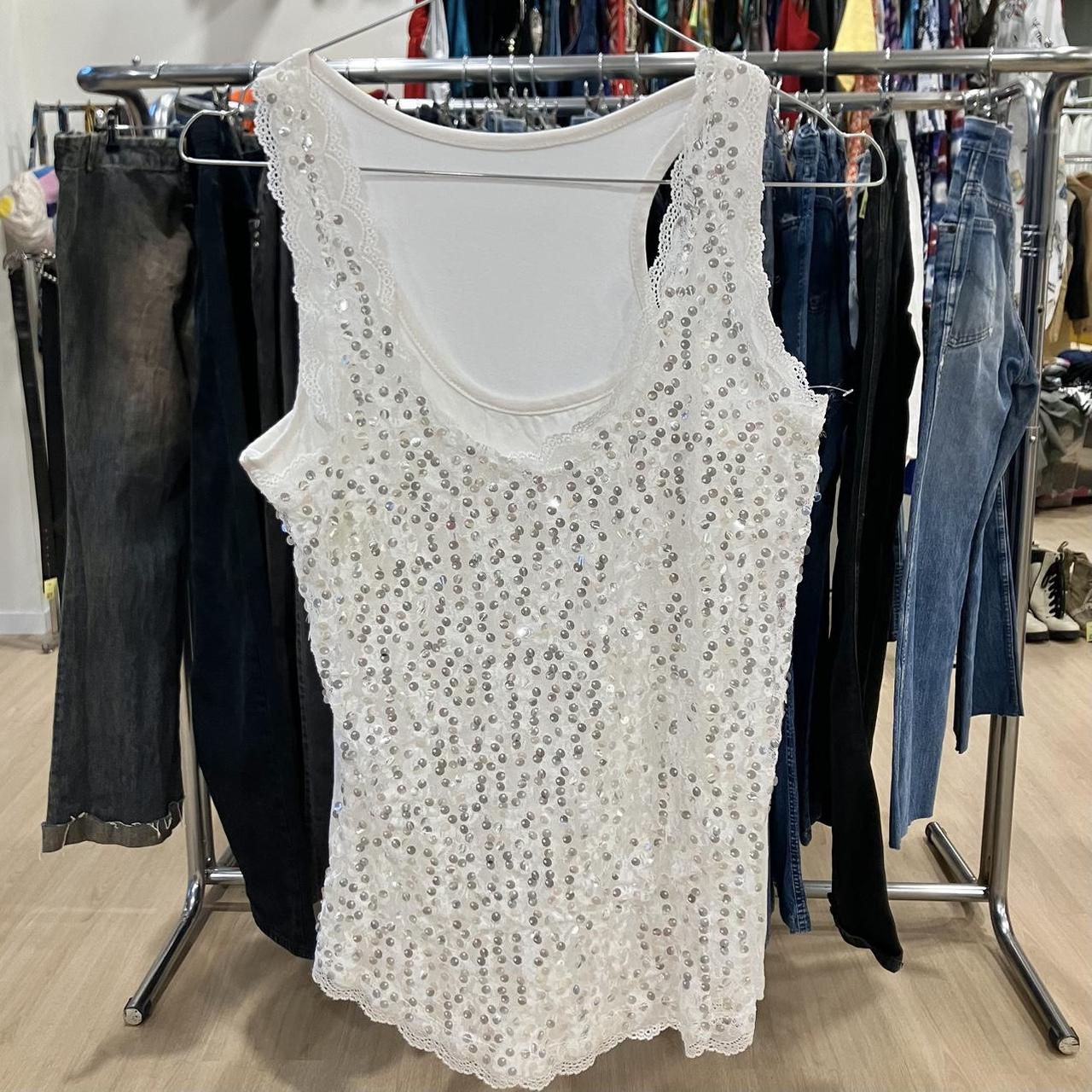 White sequin sleeveless top with lace trim displayed in a second hand clothing store