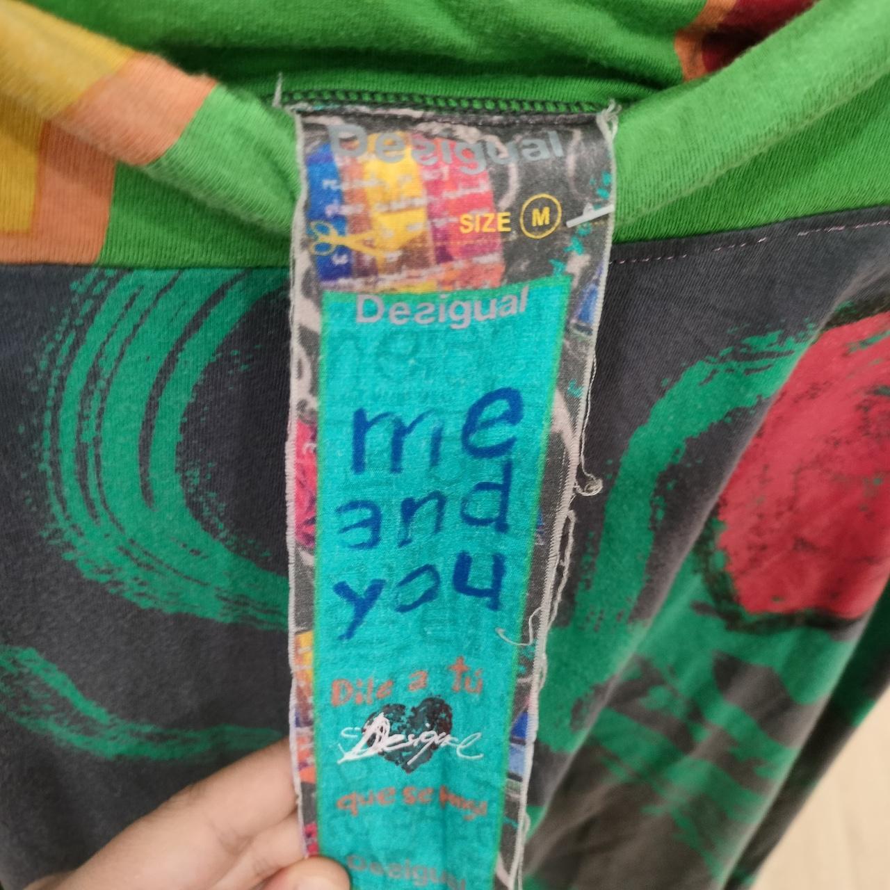 Colorful jacket with a visible brand label reading 'me and you' held by a hand