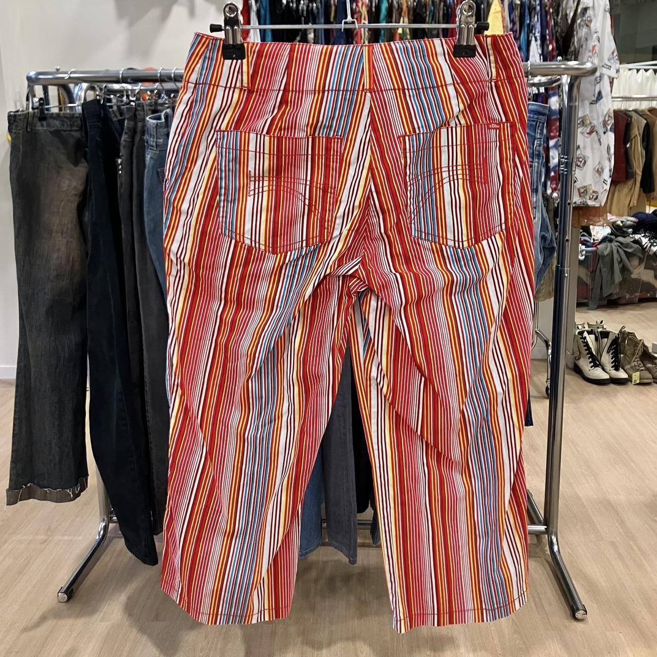 Colorful striped pants with red, yellow, blue, and white lines on display in second hand clothing store