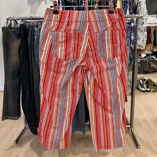 Colorful striped pants with red, yellow, blue, and white lines on display in second hand clothing store